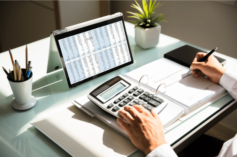 A person calculating their debt to income ratio by dividing their total monthly debt payments by their gross monthly income